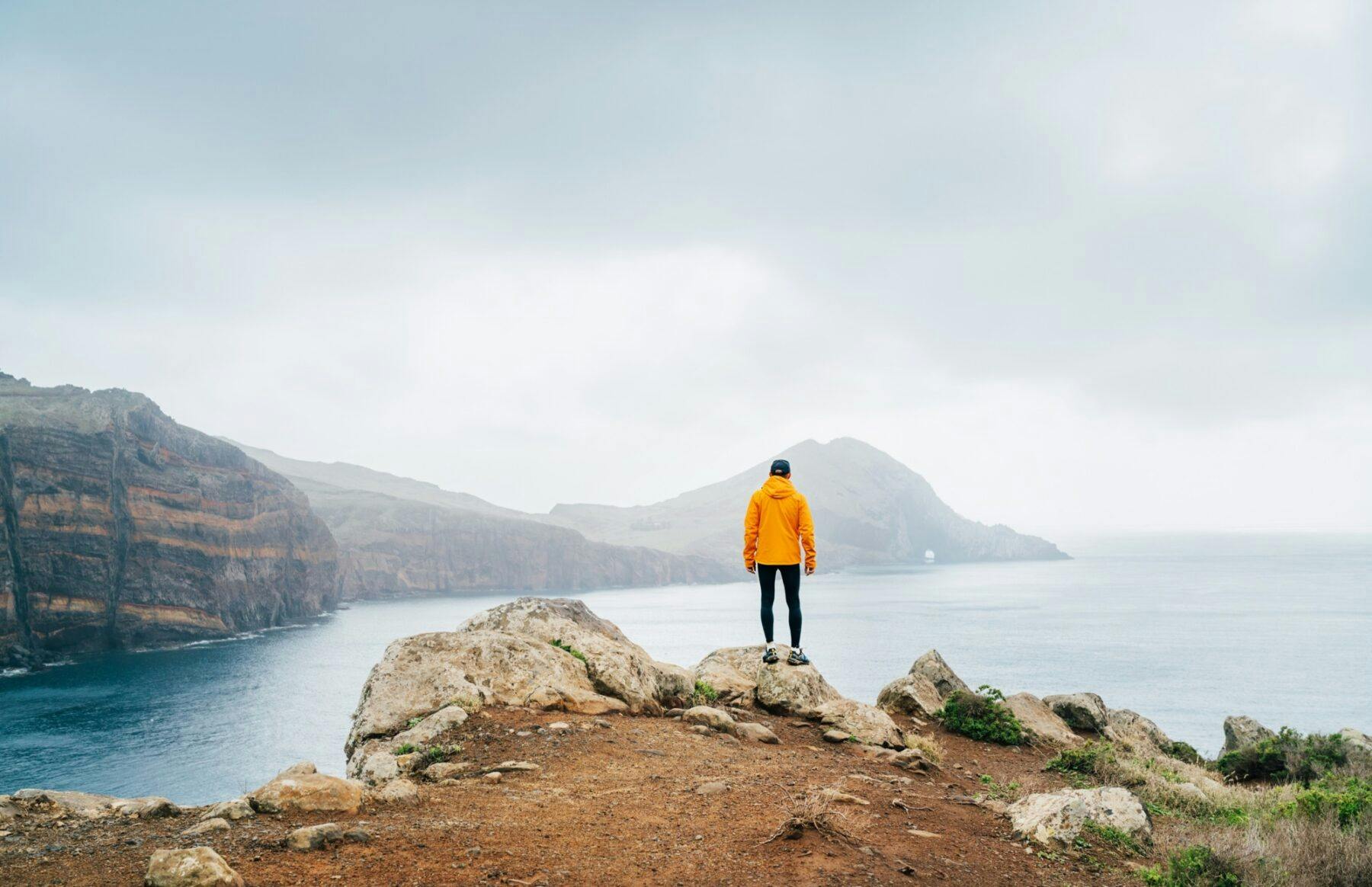 trail runner clad in an orange waterproof jacket running tights and shoes